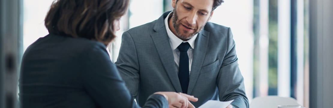 Businessman and businesswoman reviewing a document in an office setting.